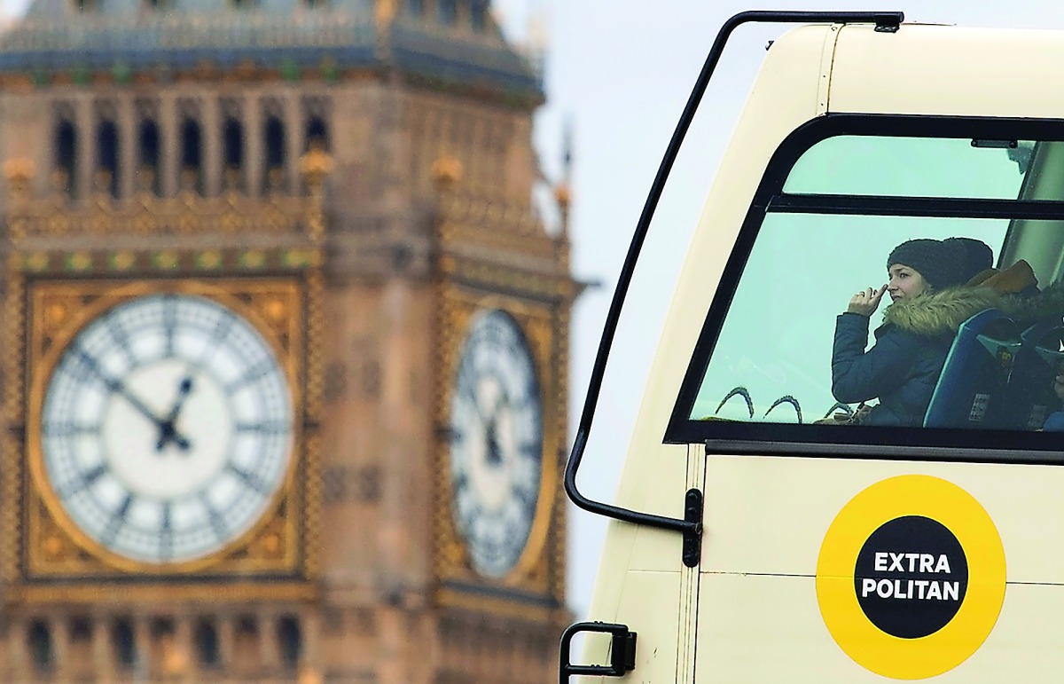 A woman riding on the top deck of a tour bus points out as she passes the Elizabeth Tower, also known as Big Ben at the Houses of Parliament in central London on March 1, 2017. The House of Lords looks set today to defy Prime Minister Theresa May by deman