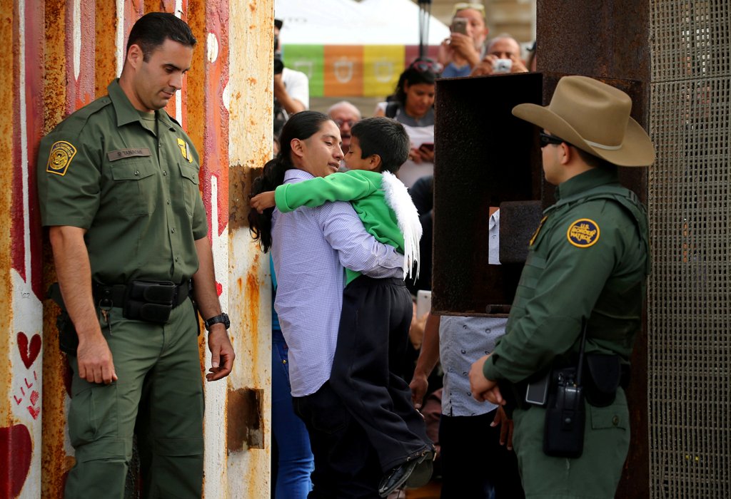 FILE PHOTO - U.S. Border patrol agents stand at an open gate on the fence along the Mexico border to allow Luis Eduardo Hernandez-Bautista hug Ty'Jahnae Williams and his father Eduardo Hernandez (not in view), as part of Universal Children's Day at the Bo