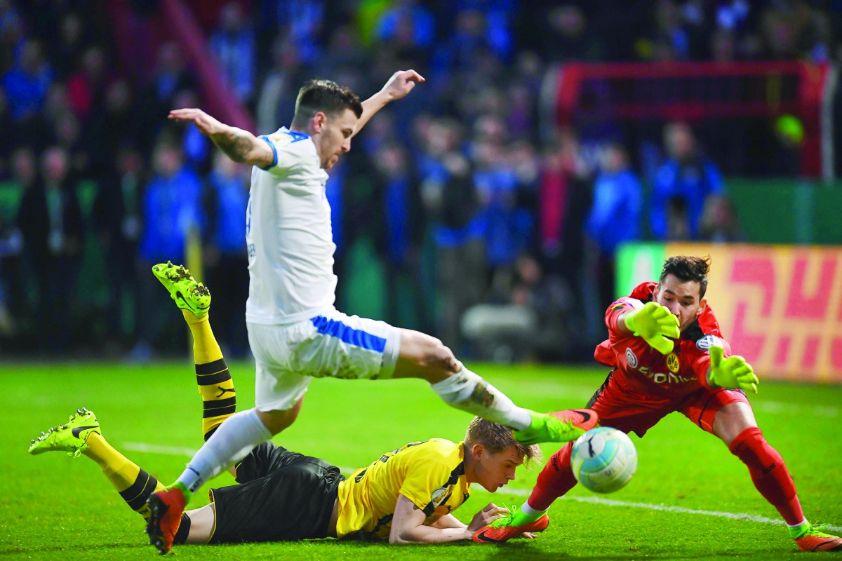 Dortmund's defender Matthias Ginter, Dortmund goalkeeper Roman Buerki (right) and Lottes Bernd Rosinger vie for the ball during the German Cup DFB Pokal quarter-final football match in Osnabruck, northern Germany. 