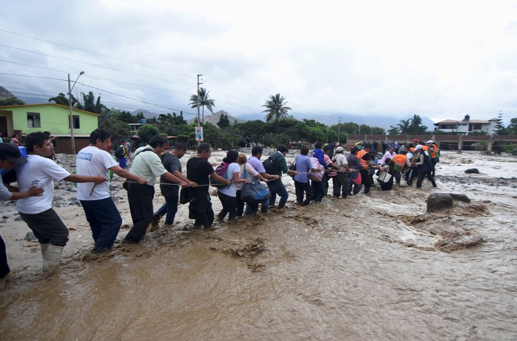 Residents cross a flooded street after a massive landslide and flood in Trujillo, northern Peru, March 17, 2017. REUTERS/Douglas Juarez 
