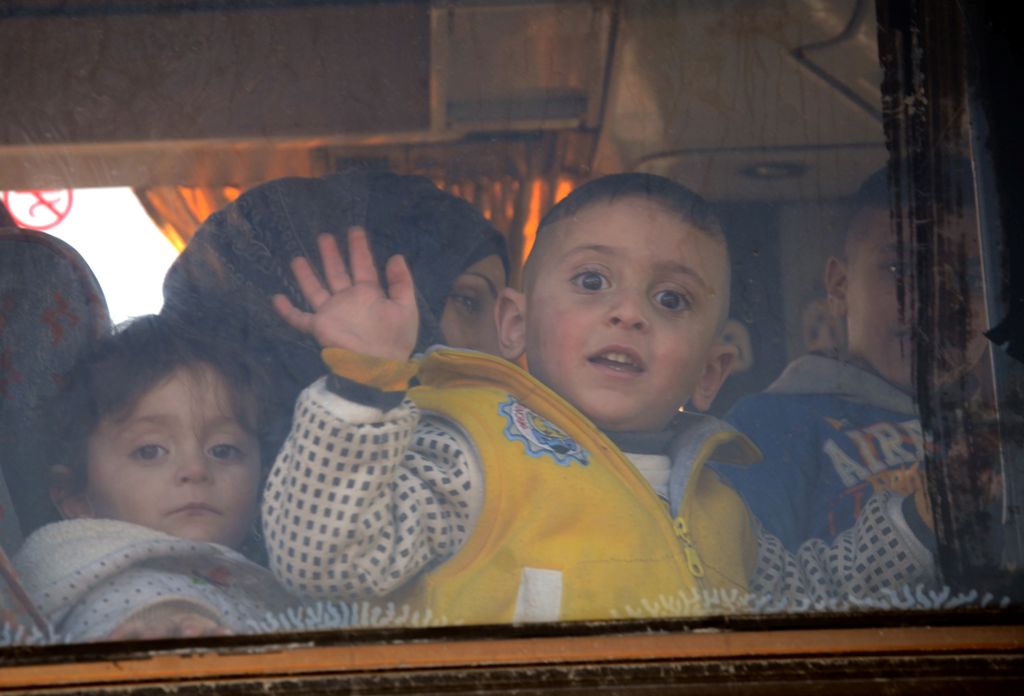 A child waves from the window of a bus as Syrians who were evacuated from Waer, the last opposition-held district of Homs, arrive in the northern Syrian town of al-Bab on March 19, 2017, under a controversial Russian-supervised deal to bring Syria's third