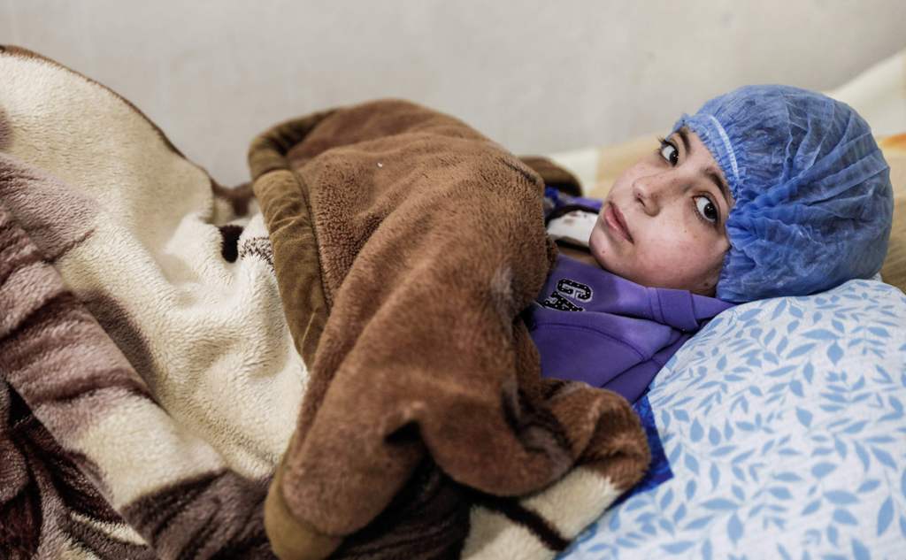 Dania, a 14-year-old Syrian who suffers from renal insufficiency, sits on a bed as she receives a dialysis session inside a basement-turned-clinic in the rebel-held town of Douma, on the outskirts of the capital Damascus, on March 16, 2017.  AFP / Sameer 