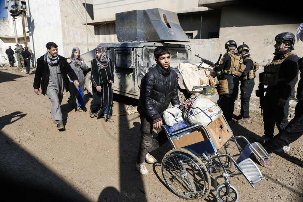  Displaced Iraqi families carry their belongings as they evacuate a neighbourhood in western Mosul as Iraqi forces advance on March 24, 2017, during an offensive to retake the city from Islamic State (IS) group fighters. / AFP / AHMAD GHARABLI
