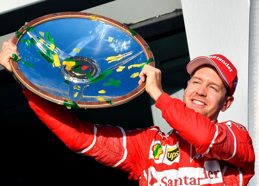 Ferrari's German driver Sebastian Vettel celebrates with the winner's trophy on the podium following his victory in the Australian Grand Prix in Melbourne on March 26, 2017.  AFP / SAEED KHAN