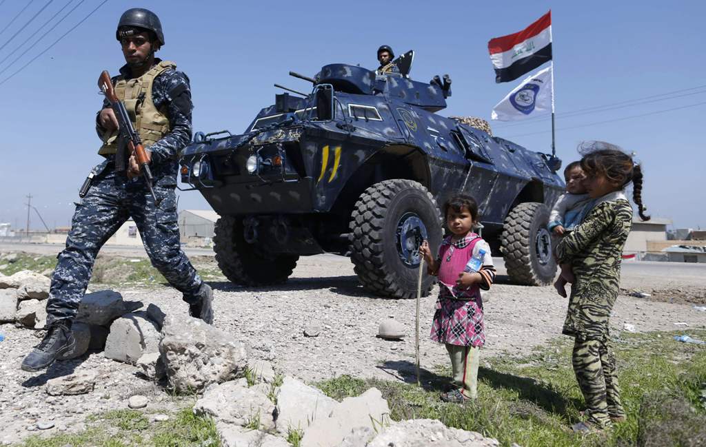 Displaced Iraqi children, who fled their homes in the Old City in western Mosul due to the ongoing fighting between government forces and Islamic State (IS) group fighters, are seen looking towards a security forces member ahead of being taken to the Hamm