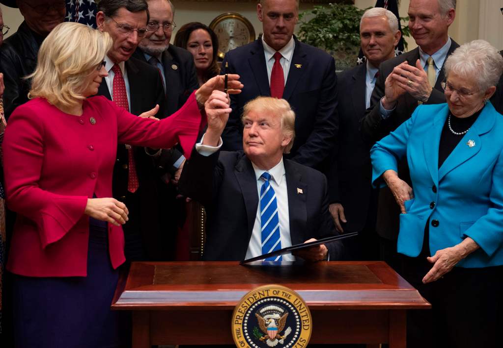 US President Donald Trump (C) gives a pen to US Congresswoman Liz Cheney, R-Wyoming, after signing H.J. Resolution 37, 44, 57 and 58 at the White House in Washington, DC, March 27, 2017. / AFP / JIM WATSON
