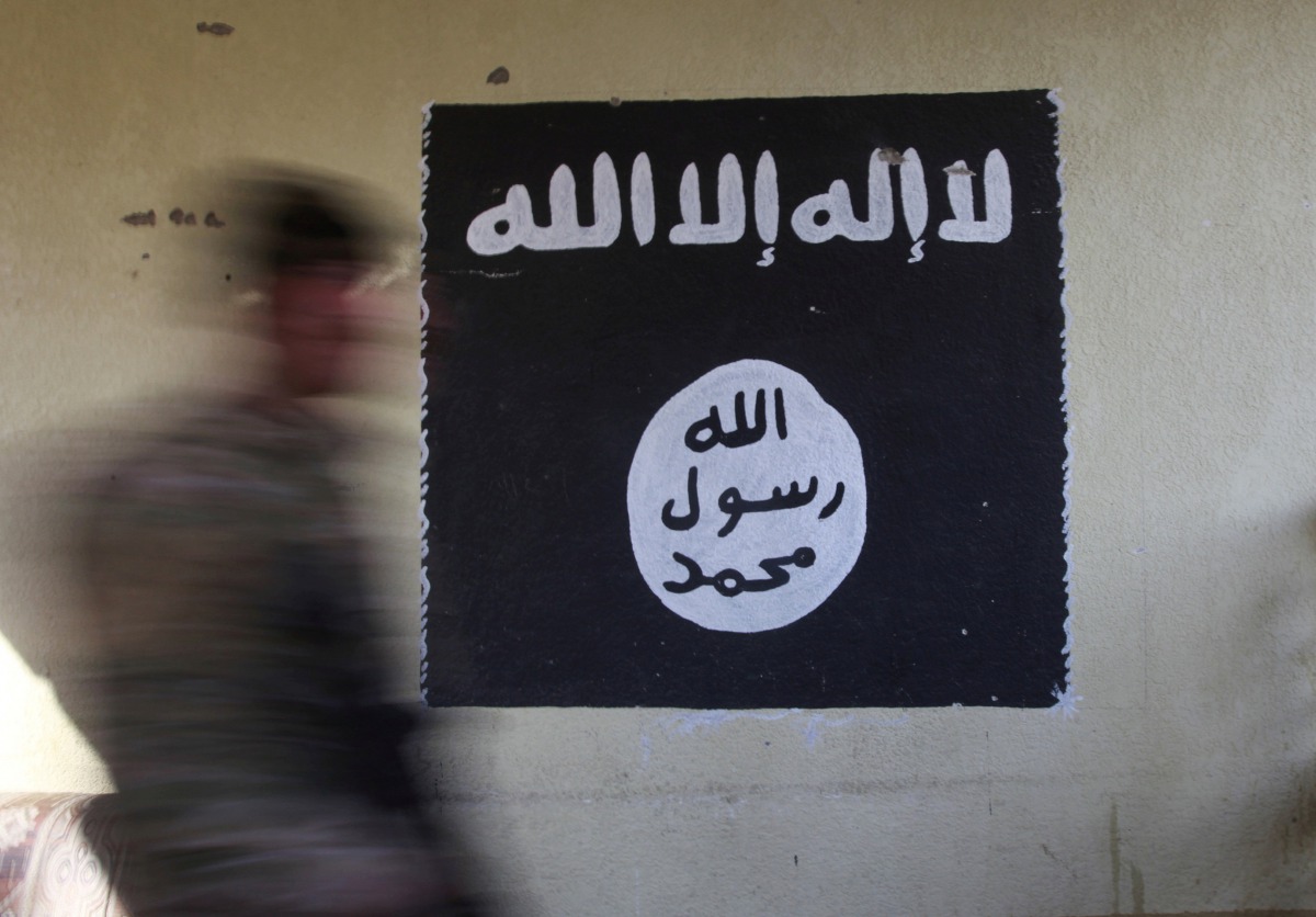 An Iraqi forces member walks past a wall painted with the black flag used by Islamic State militants at a hospital damaged by clashes in the Wahda district of eastern Mosul, January 8, 2017 (REUTERS) 