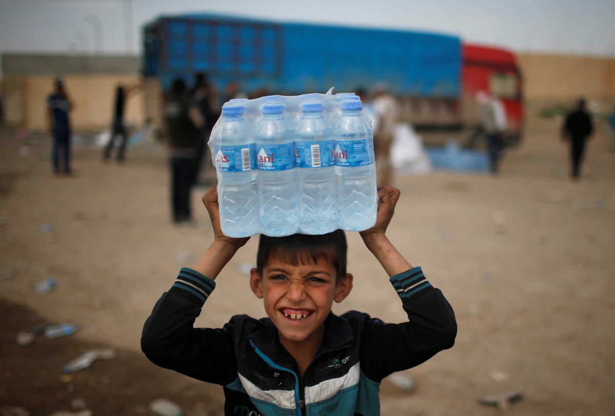 A displaced Iraqi boy smiles after receiving water, as Iraqi forces battle with Islamic State militants, in western Mosul, Iraq March 28, 2017. REUTERS/Suhaib Salem