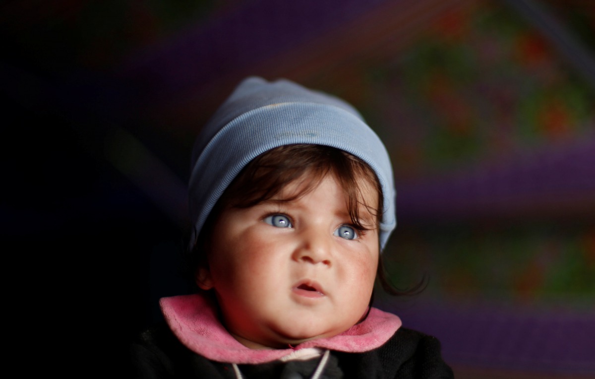 Displaced Iraqi baby who had fled her home is carried by her brother inside a tent in at Hammam al-Alil camp south of Mosul, Iraq March 29, 2017. REUTERS/Suhaib Salem