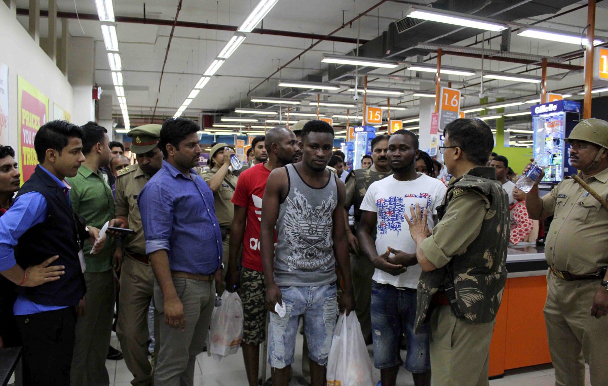 This photo taken on March 27, 2017 shows Indian police and onlookers surrounding African nationals at a shopping mall in Greater Noida. Hundreds of residents of an Indian city where a teenage boy died of a suspected drug overdose went on a violent rampage