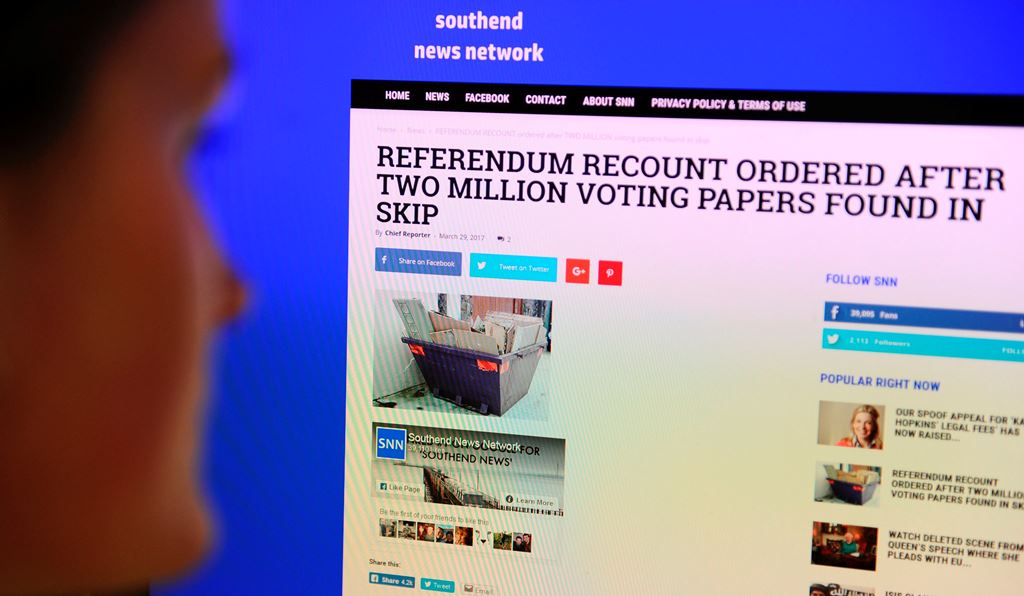 A journalist poses reading a satirical fake news story on the Southend News Network website in London on March 31, 2017. AFP / DANIEL SORABJI 