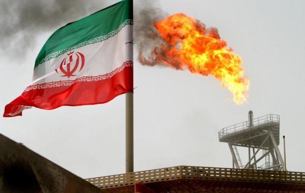 FILE PHOTO: A gas flare on an oil production platform in the Soroush oil fields is seen alongside an Iranian flag in the Persian Gulf, Iran July 25, 2005. REUTERS/Raheb Homavandi/File Photo.