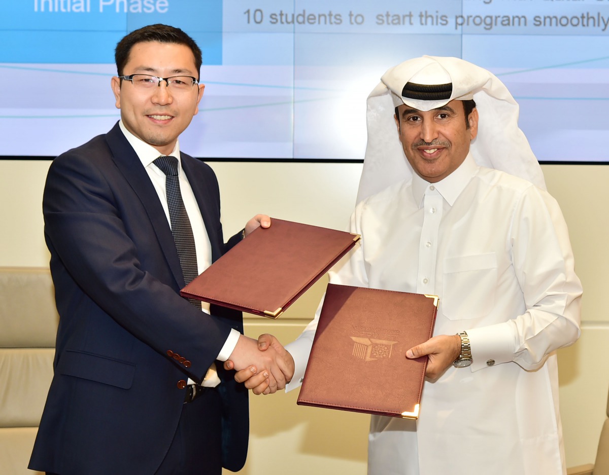 Dr Khalifa Al-Khalifa and Zong Yan exchanging documents.