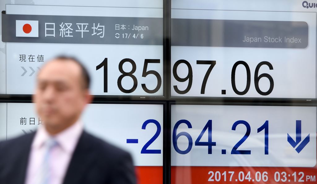 A businessman walks past a stock quotation board flashing the Nikkei 225 key index of the Tokyo Stock Exchange in front of a securities company in Tokyo on April 6, 2017. AFP / Toru YAMANAKA
