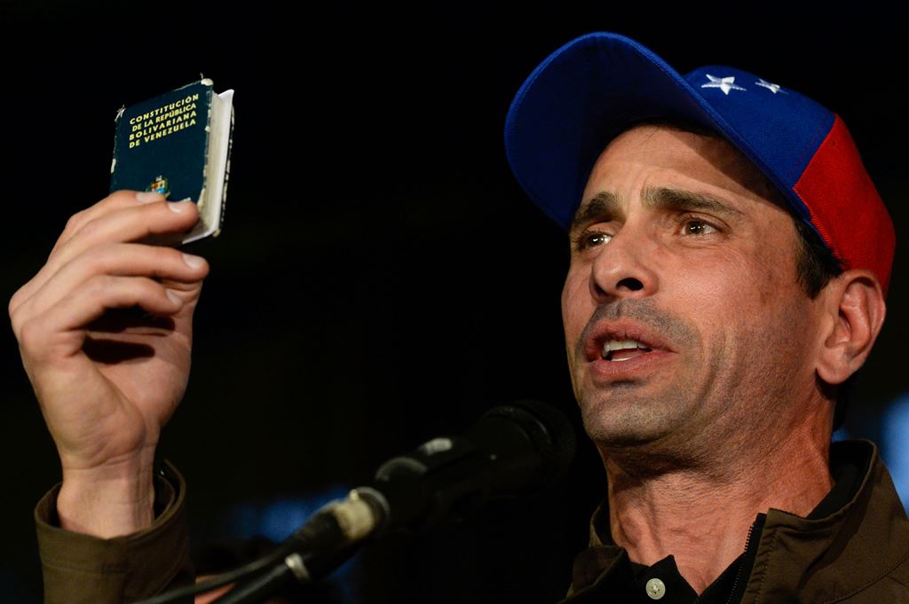 Venezuelan opposition leader and former presidential candidate Henrique Capriles holds a copy of the constitution during a press conference in Caracas on April 7, 2017. AFP / FEDERICO PARRA