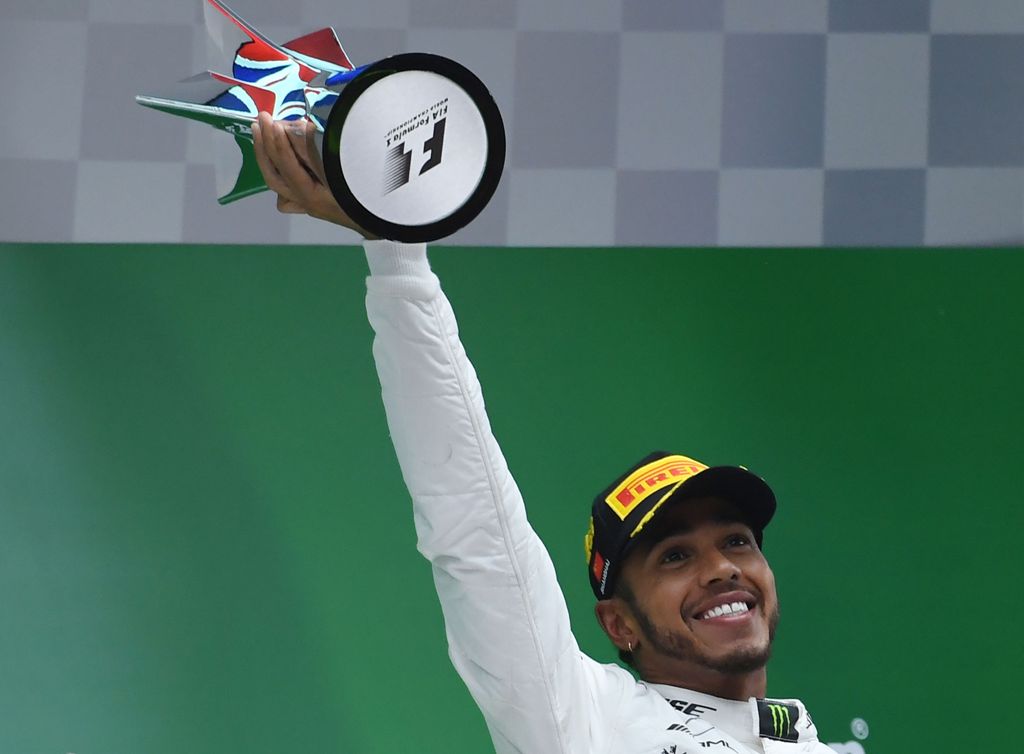Mercedes' British driver Lewis Hamilton raises the trophy after winning the Formula One Chinese Grand Prix as he celebrates on the podium in Shanghai on April 9, 2017. / AFP / WANG ZHAO