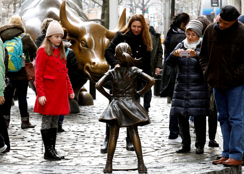 FILE PHOTO: People look at a statue of a girl facing the Wall St. Bull, as part of a campaign by U.S. fund manager State Street to push companies to put women on their boards, in the financial district in New York, U.S., March 7, 2017. REUTERS/Brendan McD