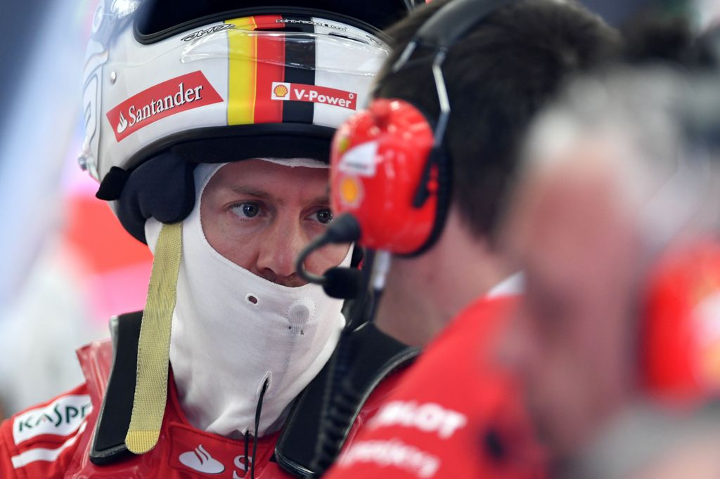 Ferrari's German driver Sebastian Vettel talks to one of his engineers in the garage during a practice session ahead of the Formula One Bahrain Grand Prix at the Sakhir circuit in the desert south of the Bahraini capital, Manama on April 14, 2017. / AFP /