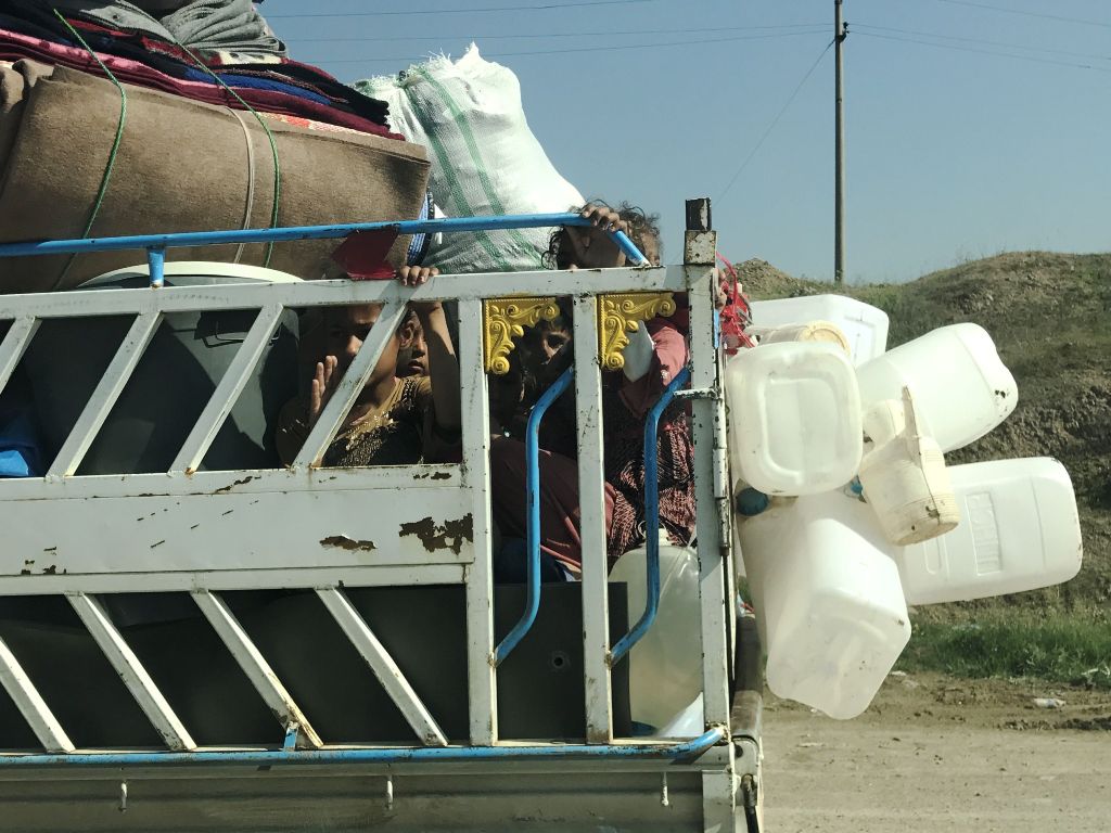 Iraqi children are seen on the back of a pick up truck as they head back to Mosul on April 16, 2017. / AFP / Christophe SIMON
