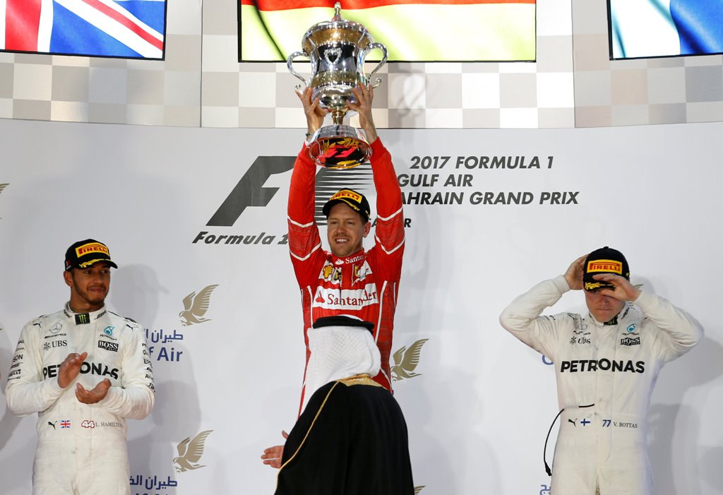 First place Ferrari Formula One driver Sebastian Vettel of Germany (C) holds the trophy on the podium with second place Mercedes Formula One driver Lewis Hamilton of Britain (L) and third place Mercedes Formula One driver Valtteri Bottas of Finland. REUTE