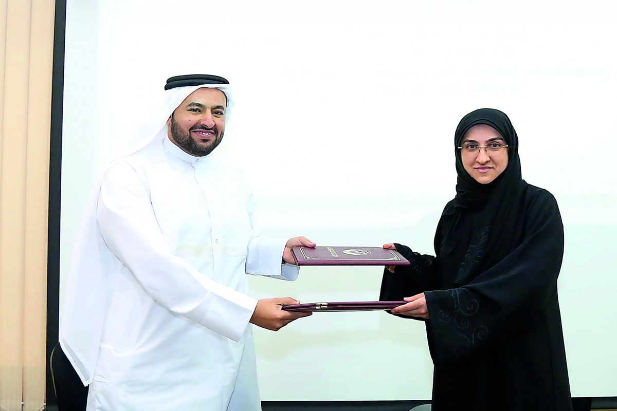 Dr Mohamed Abdulaziz Al Khulaifi, Dean of the College of Law, and Fatima Abdulaziz Bilal, Director of the Legal and Judicial Studies Centre, exchanging the documents. 