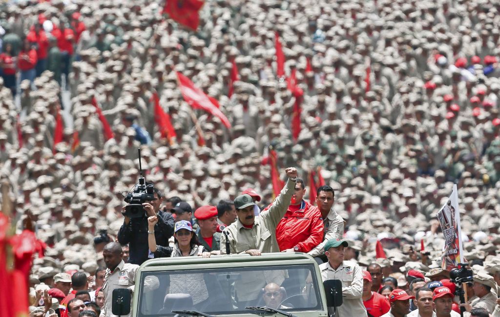 Handout picture released by the Venezuelan Presidency showing Venezuelan President Nicolas Maduro (C) saluting next to his wife Cilia Flores as they arrive for the celebrations for the seventh anniversary of the Bolivarian Militia in Caracas on April 17, 