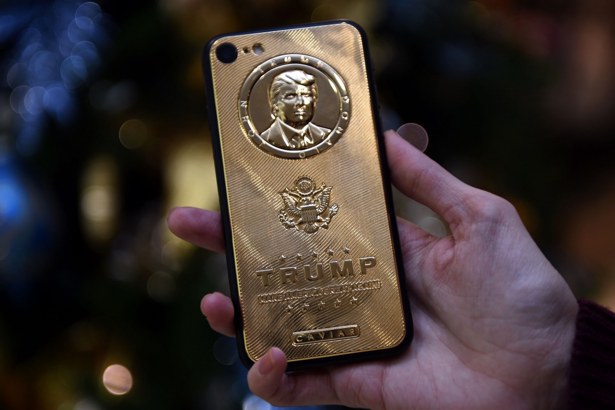 FILE PHOTO: An employee of Caviar Phones, a Russian-Italian company specializing in smartphone customization, displays a special gold-plated iPhone 7 smartphone bearing the likeness of  Trump (AFP) 