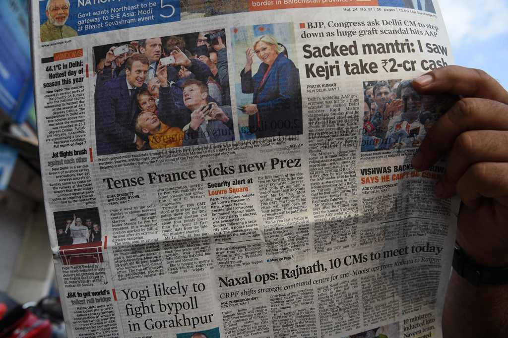 An Indian man reads a newspaper with the front page news of Emmanuel Macron winning the French Presidential elections in Mumbai on May 8, 2017. AFP / INDRANIL MUKHERJEE