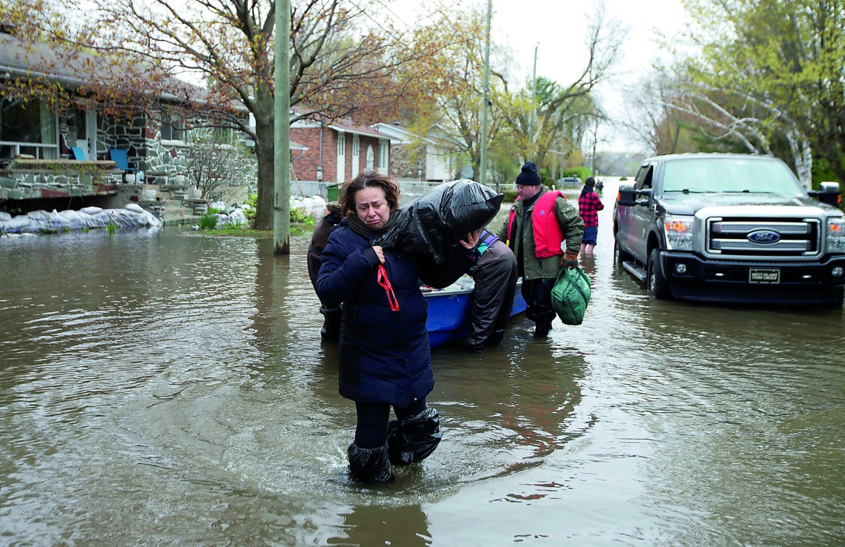 Mina Tayarani carrying a bag of her belongings as she is evacuated from her home in a flooded residential neighbourhood in Ile Bizard, Quebec, yesterday.