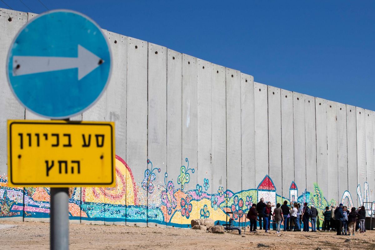 Israeli tourists take pictures of graffiti on part of Israeli barrier in the Israeli Kibbutz of Netiv Haashara along the border between Israel and the Gaza Strip on February 7, 2017 (AFP / Jack Guez) 