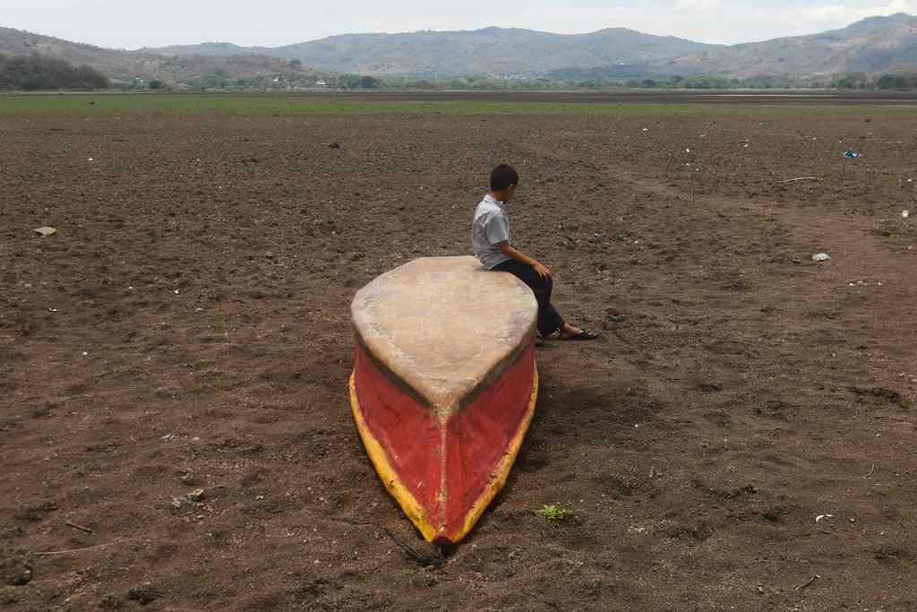 A boy sits on an abandoned boat on what is left of Lake Atescatempa, which has dried up due to drought and high temperatures, in Atescatempa, 174 km southeast of Guatemala City, on May 5, 2017. AFP / Marvin RECINOS