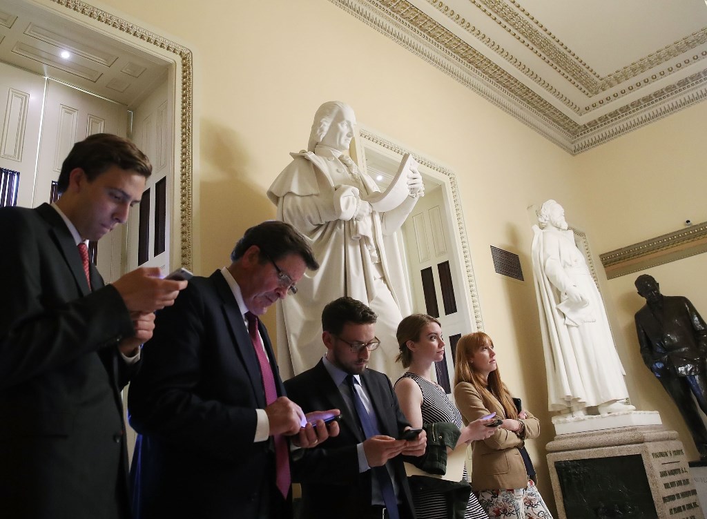 People look at their devices as news comes in that the Justice Department announced that former FBI director Robert Mueller will be a special counsel overseeing the Russia investigation. Mark Wilson/Getty Images/AFP