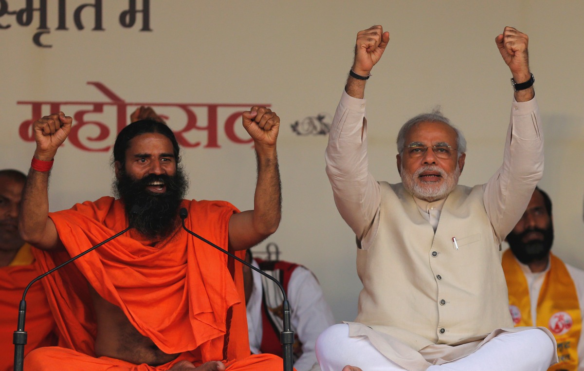  Narendra Modi and Indian yoga guru Baba Ramdev (L) raise their hands as they chant patriotic slogans during a Yoga Mahotsav or festival, in New Delhi March 23, 2014. REUTERS/Adnan Abidi