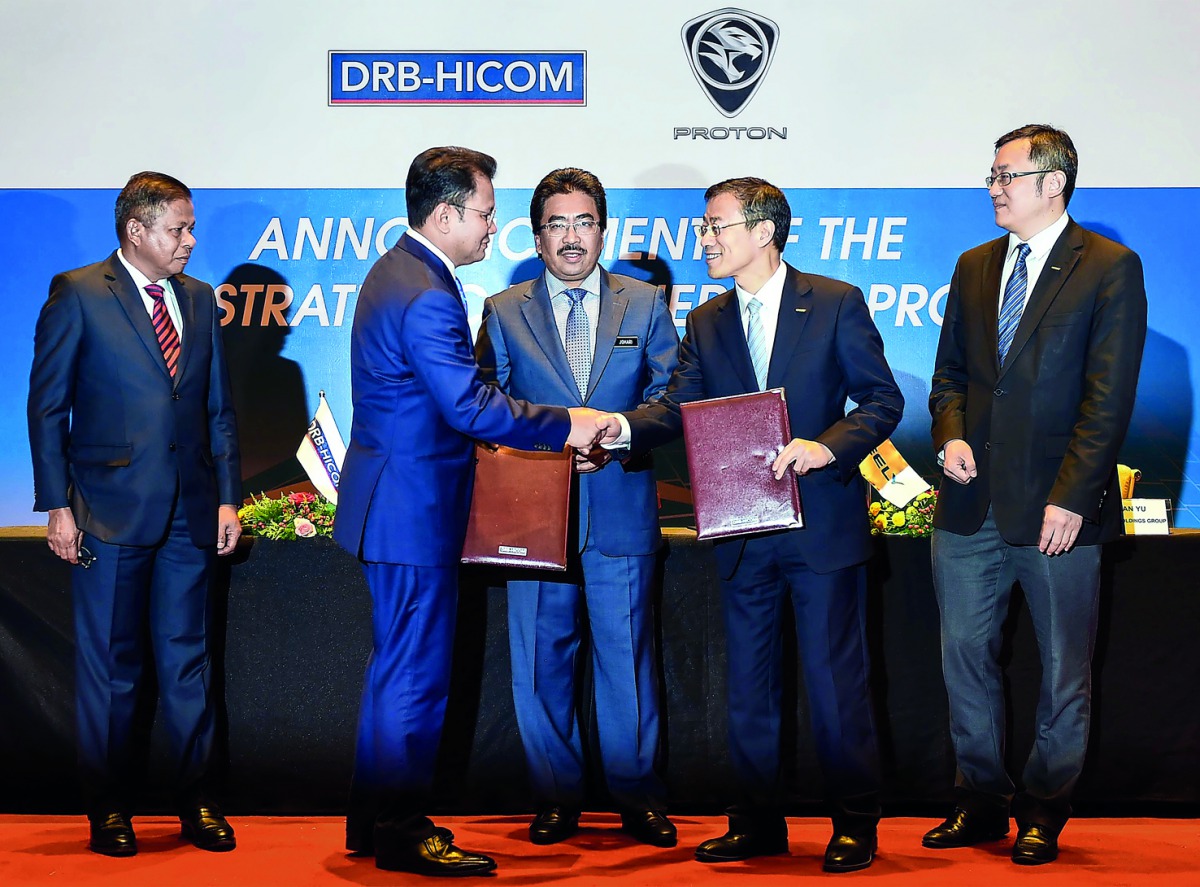 Group Managing Director DRB-HICOM Berhad Syed Faisal Albar (second left) and Executive Vice President and CFO Zhejiang Geely Holding Group Daniel Li (Li Donghui) shake hands as Malaysia's Minister of Finance II Johari Abdul Ghani (centre), witnessing the 