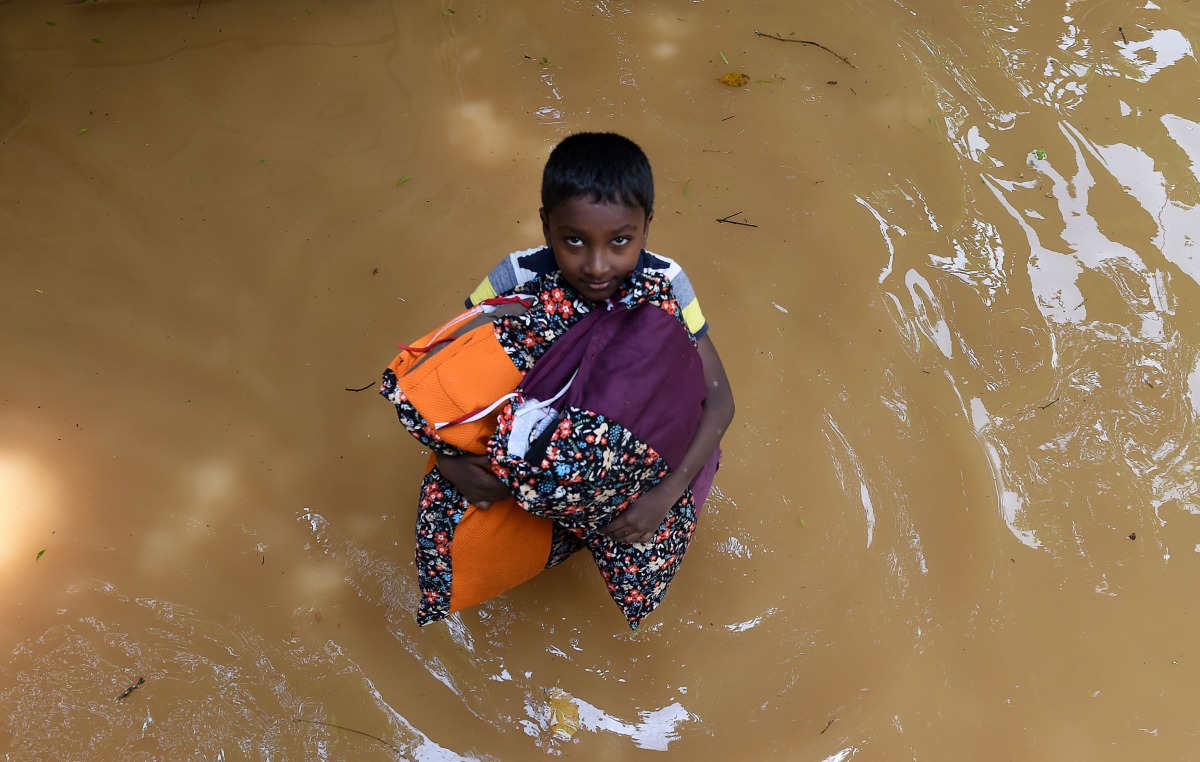 A Sri Lankan boy carries pillows through floodwaters from his home in Kelaniya on May 27, 2017.  AFP / Ishara S. Kodikara