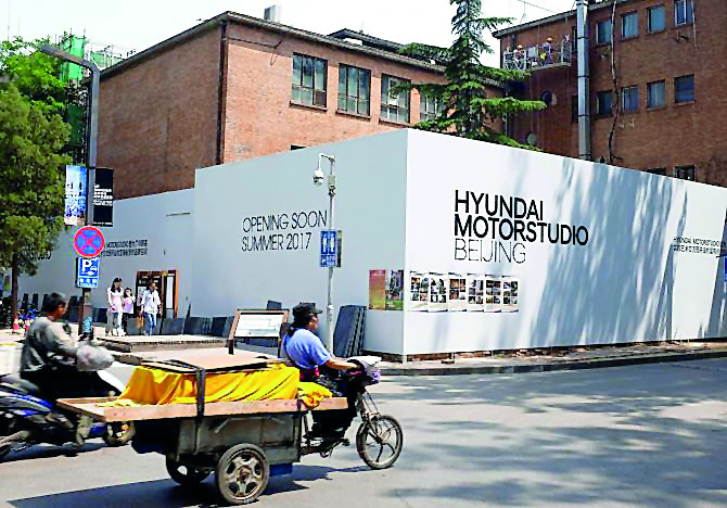 A tricycle drives past the construction site of the Hyundai Motor Studio in Beijing, China.