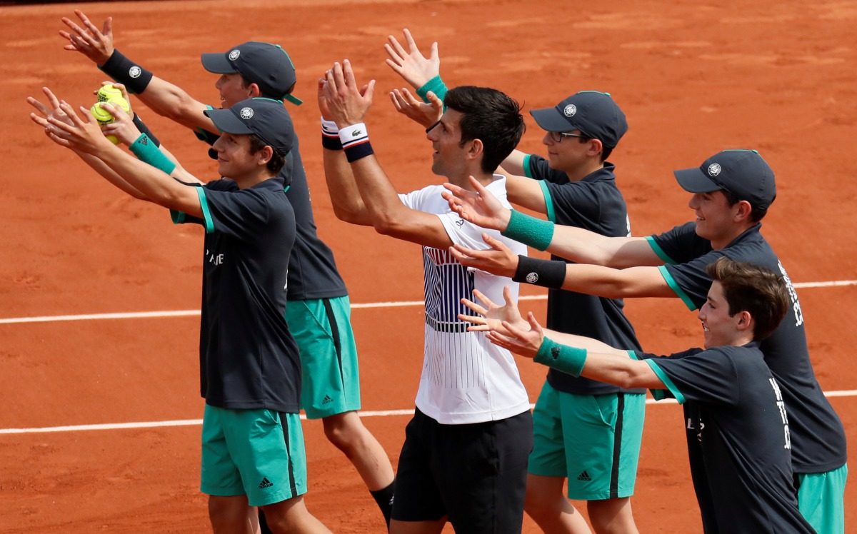 Serbia's Novak Djokovic celebrates winning his first round match against Spain's Marcel Granollers with ball boy. (Reuters / Gonzalo Fuentes)