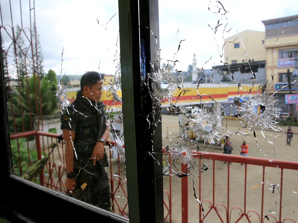 A policeman stands on guard behind a window full of bullet holes as government soldiers assault the Maute group in Marawi City, Philippines May 31, 2017. REUTERS/Romeo Ranoco TPX IMAGES OF THE DAY
