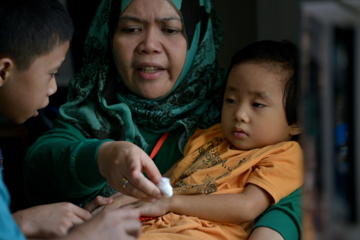 A volunteer doctor tends to a boy that was trapped for 11 days with his family at Pangarungan Village in Marawi City, on the southern island of Mindanao on June 3, 2017. AFP / RODY
