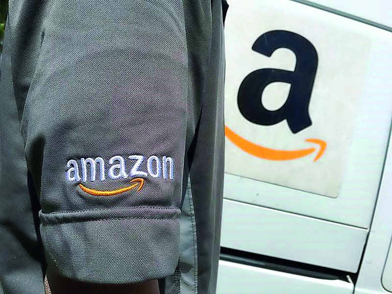 A file photo of an Amazon.com Inc driver stands next to an Amazon delivery truck in Los Angeles, California, US.