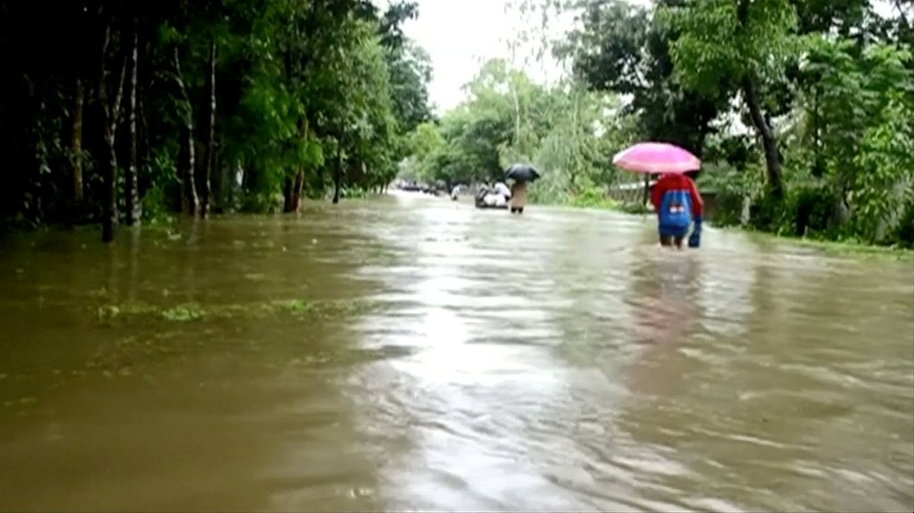 People walk in floodwaters following landslides triggered by heavy rain in Khagrachari, Bangladesh, in this still frame taken from video June 13, 2017. REUTERS/REUTERS TV.