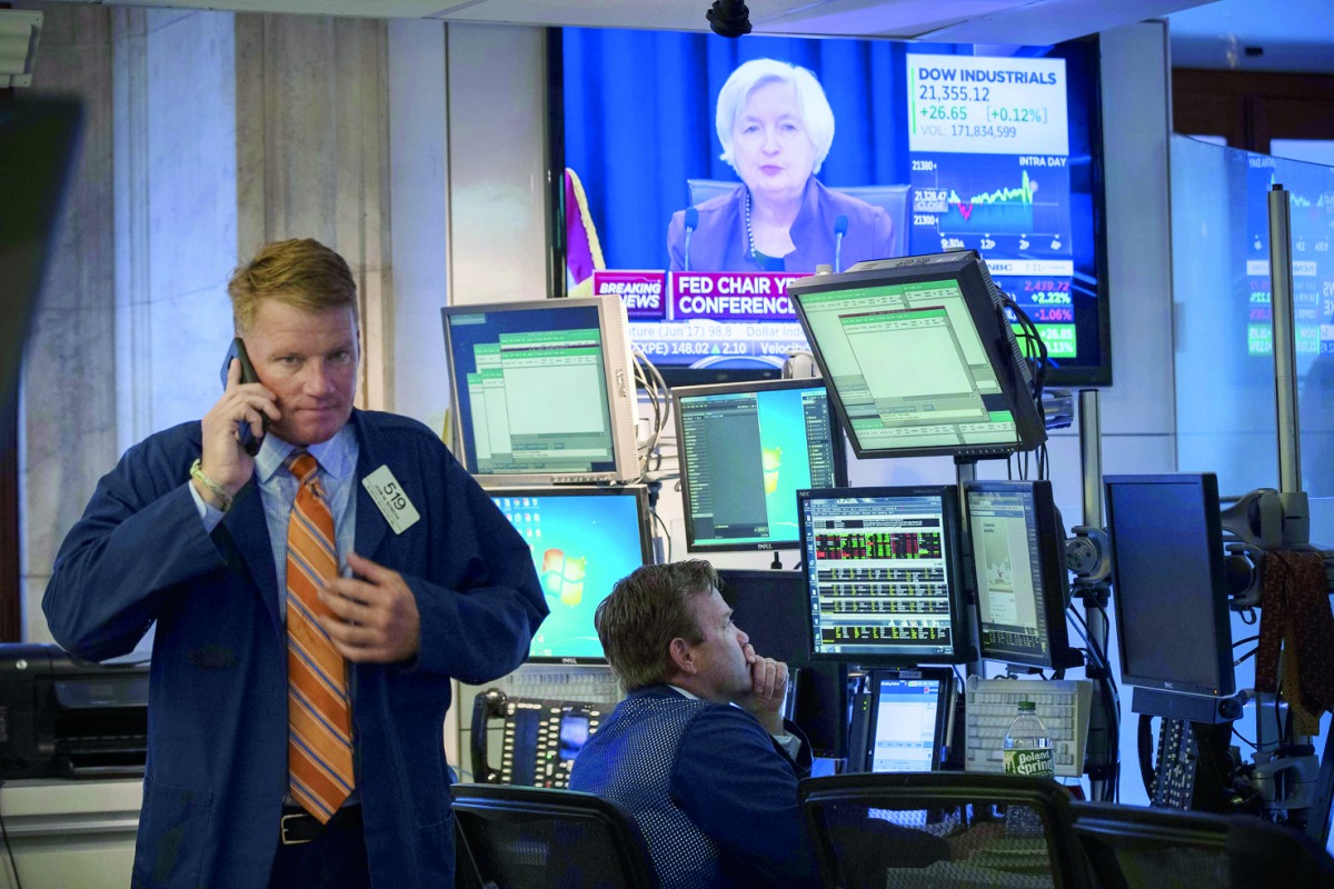 Traders work as a television monitor displays Federal Reserve Chair Janet Yellen announcing the Fed's decision to raise interest rates on the floor of the New York Stock Exchange (NYSE) in New York City