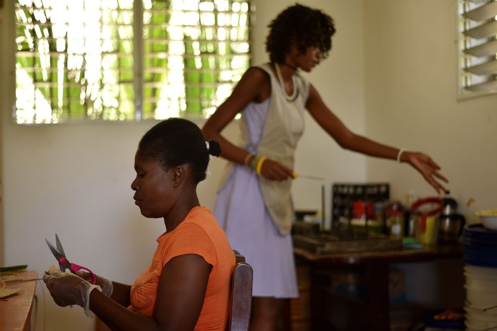 Magoina (L) and Daniella (R) work producing soap at the Anacaona company in Port-au-Prince on June 6, 2017. AFP / HECTOR RETAMAL 
