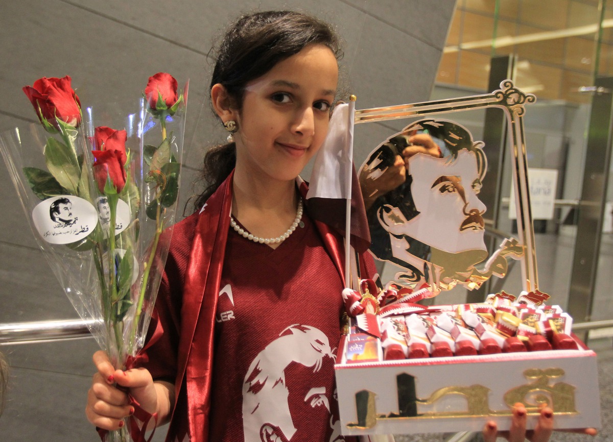 A Qatari girl holds flowers and pictures of HH the Emir Sheikh Tamim Bin Hamad Al-Thani at Hamad international airport in Doha, Qatar June 22, 2017. Reuters/Naseem Zeitoon