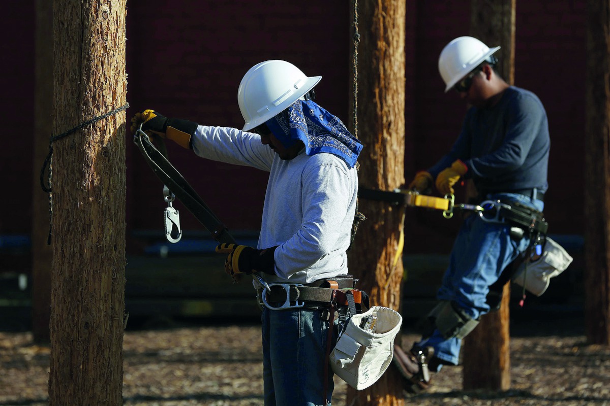 Students training to become electrical linemen attach themselves to poles during class at Los Angeles Trade-Technical College in Los Angeles, in this file photo.  