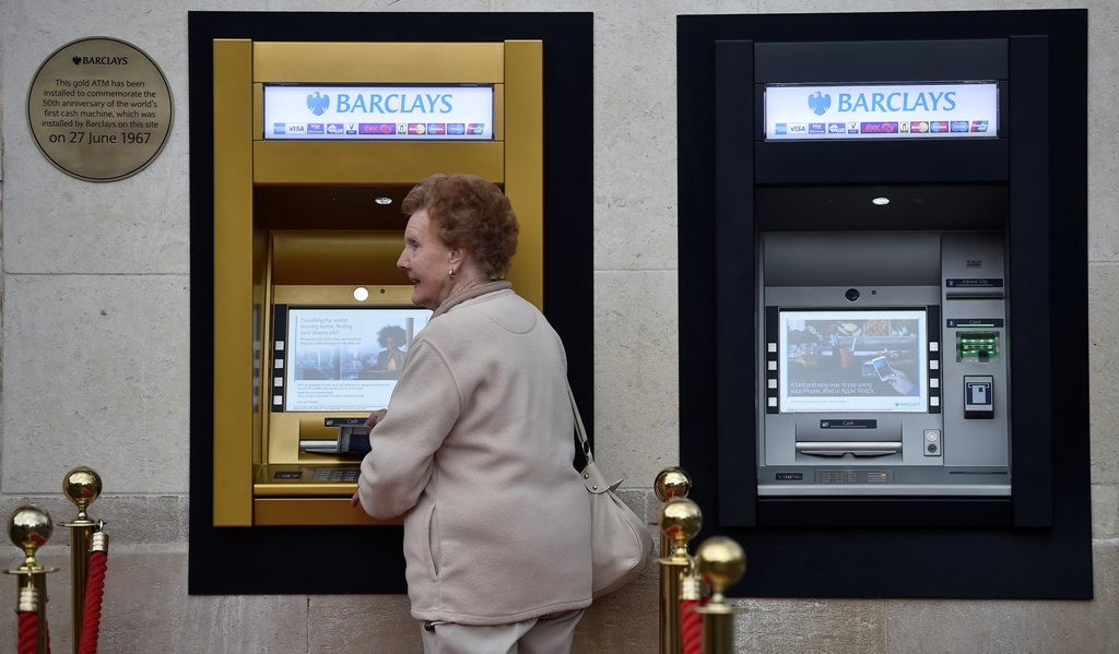 A woman uses a golden ATM, marking the location of the first 'hole in the wall,' which opened fifty years ago, in Enfield, Britain June 27, 2017. REUTERS/Hannah McKay

