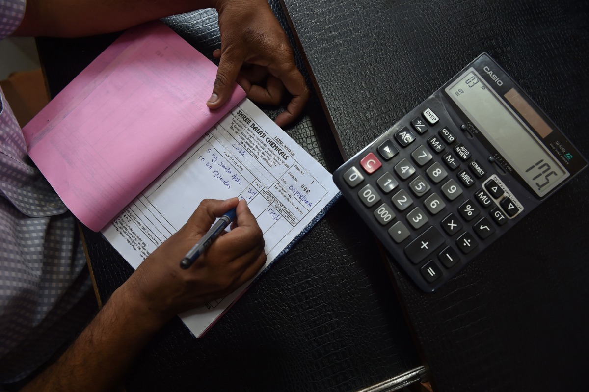 An Indian shopkeeper prepares a bill for a customer at his shop in New Delhi (AFP / SAJJAD HUSSAIN) 
