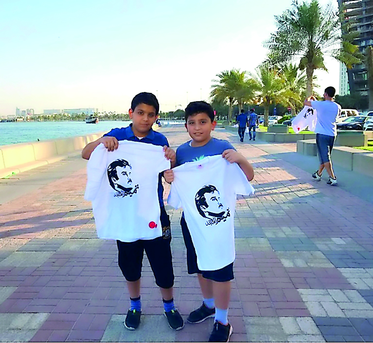 Children carrying T-shirts, distributed by Ooredoo, showing support for H H the Emir.