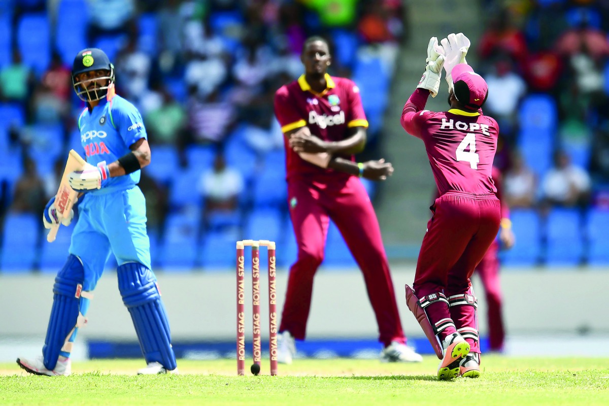 West Indies' captain Jason Holder (centre) looks on as wicketkeeper Shai Hope (right) takes a catch to dismiss India's captain Virat Kohli (left) during their fourth One Day International at the Sir Vivian Richards Cricket Ground in St. John's, Antigua, o