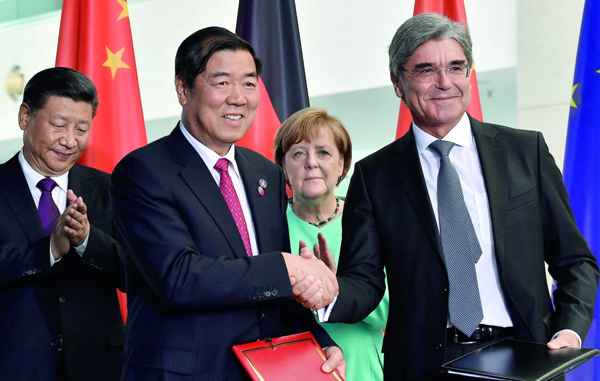 German Chancellor Angela Merkel (centre) and China's President Xi Jinping (left) look on as Siemens chairman Joe Kaeser (right) shakes hands with a Chinese business partner during a signing ceremony of German-Chinese business contracts at the Chancellery 